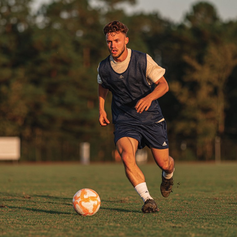 Soccer player dribbling across a grass field
